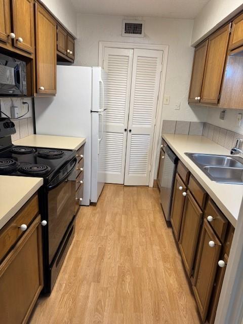 kitchen with sink, black appliances, and light hardwood / wood-style floors