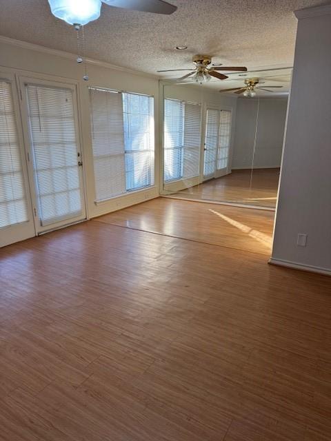 empty room featuring hardwood / wood-style flooring, ceiling fan, ornamental molding, and a textured ceiling