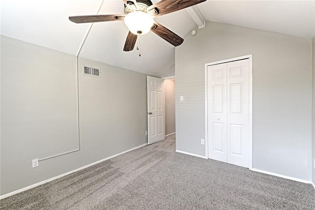 unfurnished bedroom with ceiling fan, a closet, carpet, and vaulted ceiling with beams