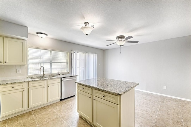 kitchen with cream cabinets, sink, stainless steel dishwasher, and light stone counters