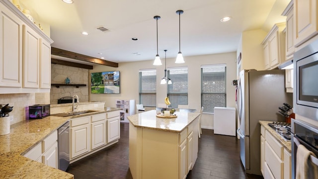 kitchen featuring pendant lighting, appliances with stainless steel finishes, light stone countertops, and sink