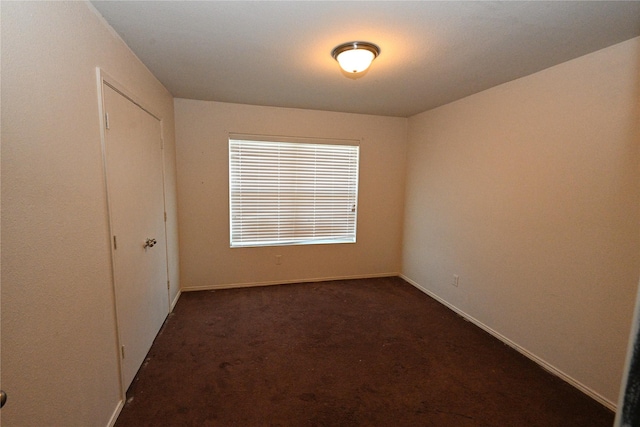 spare room featuring dark carpet