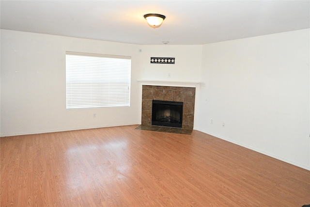 unfurnished living room featuring hardwood / wood-style flooring and a tile fireplace