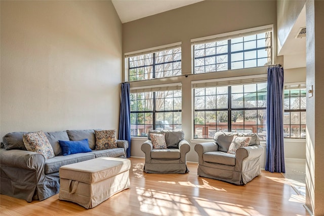 living room with light wood-type flooring and high vaulted ceiling