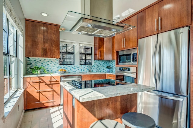 kitchen with light stone counters, appliances with stainless steel finishes, sink, and a wealth of natural light