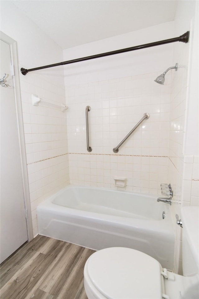 bathroom with hardwood / wood-style flooring, tiled shower / bath combo, and toilet