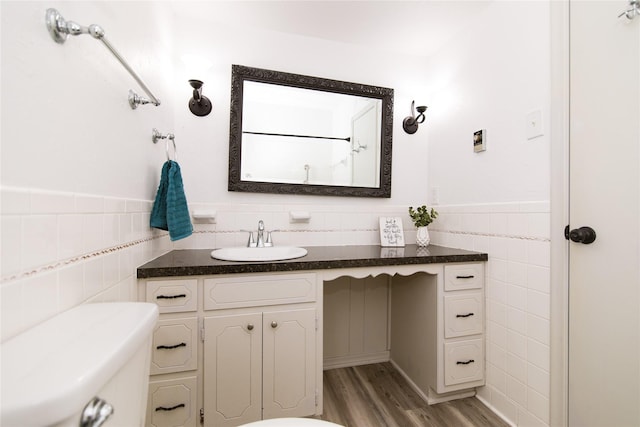 bathroom with tile walls, vanity, wood-type flooring, and toilet