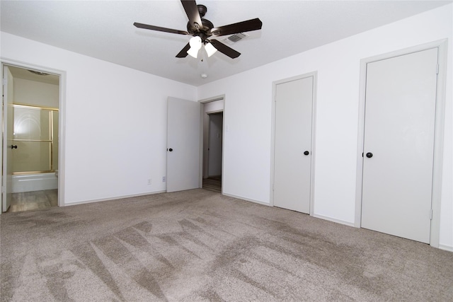 unfurnished bedroom with multiple closets, carpet flooring, connected bathroom, and ceiling fan