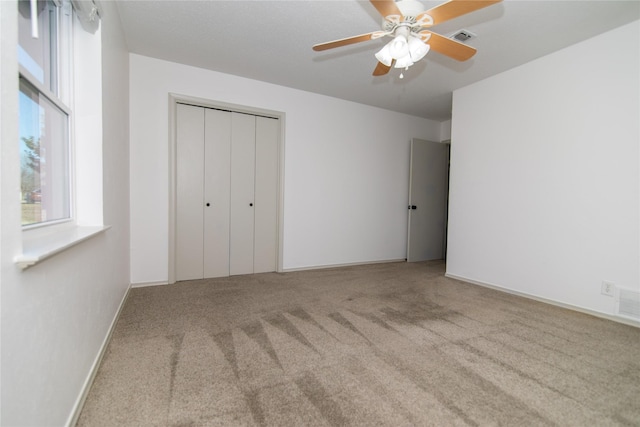 unfurnished bedroom with ceiling fan, light colored carpet, and a closet