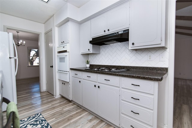 kitchen with white appliances, white cabinetry, hanging light fixtures, decorative backsplash, and light wood-type flooring