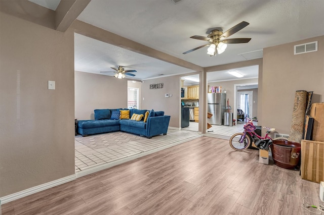 living room featuring ceiling fan, light hardwood / wood-style floors, a textured ceiling, and a wealth of natural light