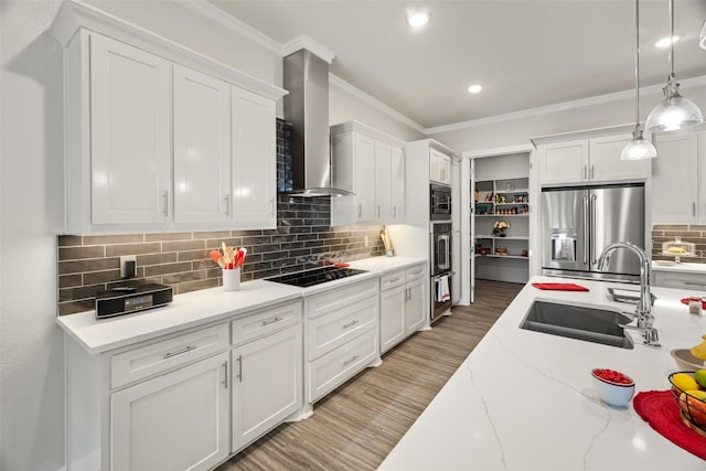 kitchen with wall chimney exhaust hood, pendant lighting, stainless steel appliances, hardwood / wood-style floors, and white cabinets