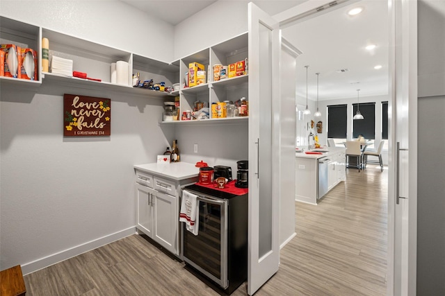 interior space featuring wine cooler, light hardwood / wood-style flooring, and white cabinets