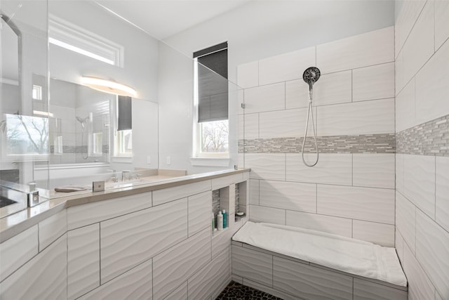 bathroom featuring tiled shower and vanity