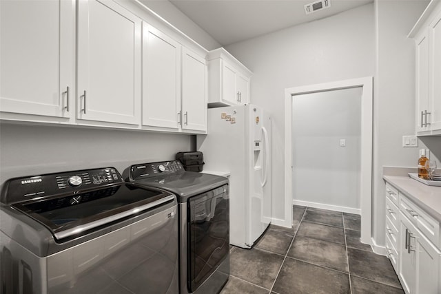 clothes washing area with cabinets, washing machine and dryer, and dark tile patterned floors