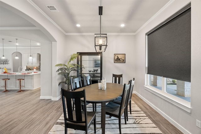 dining room with crown molding and light wood-type flooring