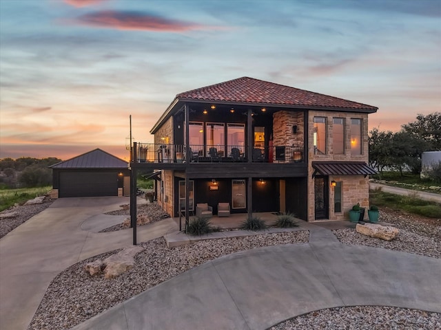 back house at dusk featuring an outbuilding and a garage