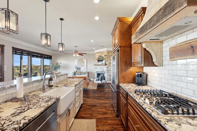 kitchen with pendant lighting, light stone counters, appliances with stainless steel finishes, and premium range hood