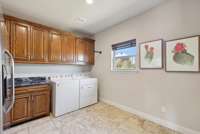 clothes washing area featuring light tile patterned flooring, cabinets, and washer and dryer