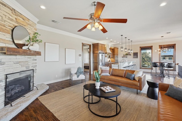 living room featuring hardwood / wood-style floors, ceiling fan with notable chandelier, a fireplace, and ornamental molding