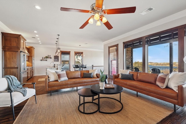 living room with sink, a water view, wood-type flooring, ornamental molding, and ceiling fan