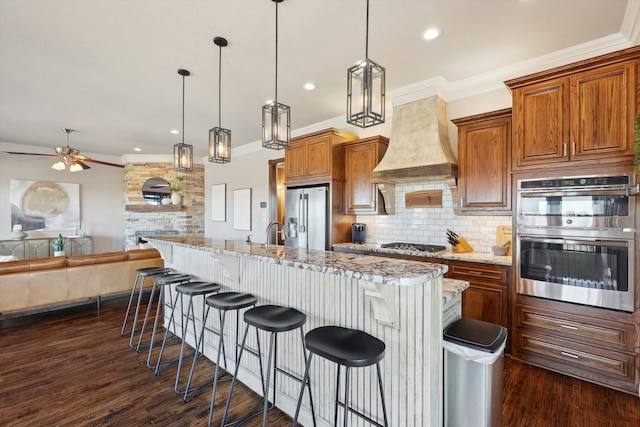 kitchen featuring hanging light fixtures, appliances with stainless steel finishes, a large island, and a kitchen bar