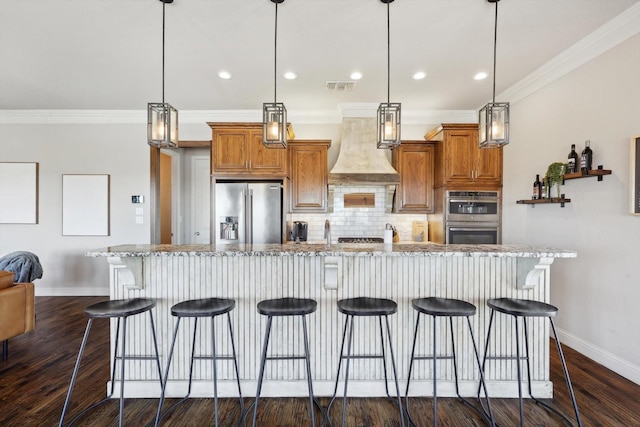 kitchen with premium range hood, appliances with stainless steel finishes, a kitchen breakfast bar, and hanging light fixtures