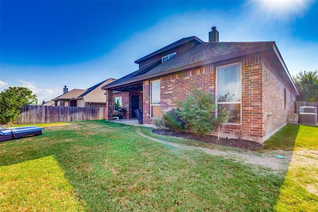 back of property with central AC, a lawn, and a patio