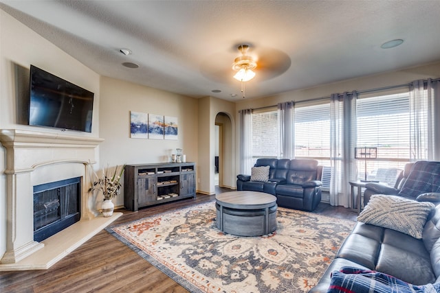 living room featuring ceiling fan, hardwood / wood-style flooring, and a textured ceiling