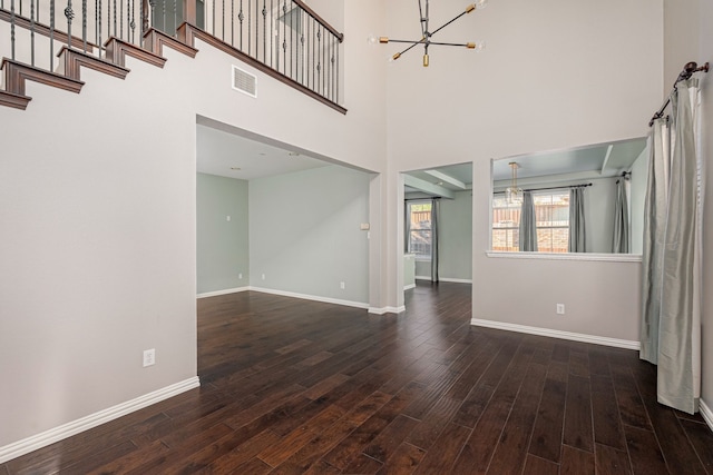 unfurnished living room featuring a high ceiling, a notable chandelier, and dark hardwood / wood-style flooring