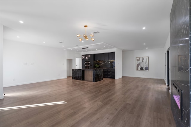 unfurnished living room with wood-type flooring and a chandelier