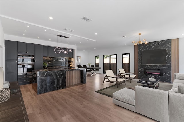 living room featuring hardwood / wood-style floors, a fireplace, sink, and a chandelier