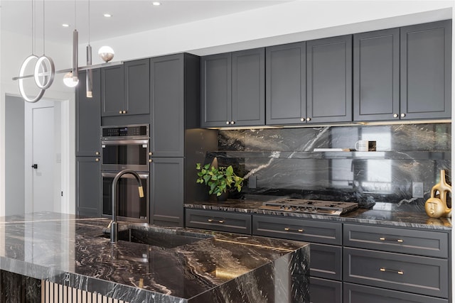 kitchen featuring sink, gray cabinetry, hanging light fixtures, dark stone counters, and stainless steel appliances