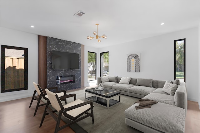 living room featuring an inviting chandelier, hardwood / wood-style flooring, a wealth of natural light, and a premium fireplace