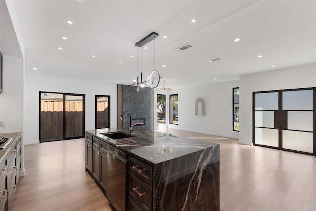 kitchen with sink, a spacious island, decorative light fixtures, stainless steel dishwasher, and dark stone counters