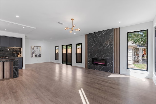 unfurnished living room with a fireplace, light hardwood / wood-style floors, and a notable chandelier