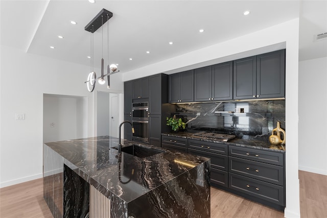 kitchen with a spacious island, appliances with stainless steel finishes, pendant lighting, and dark stone counters