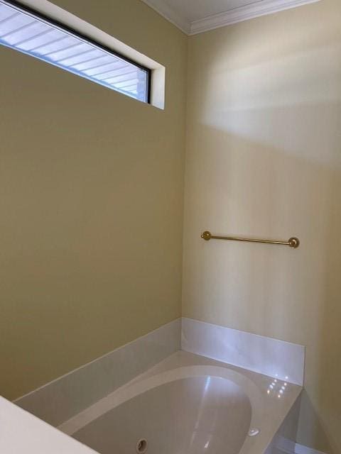 bathroom with crown molding and a tub to relax in