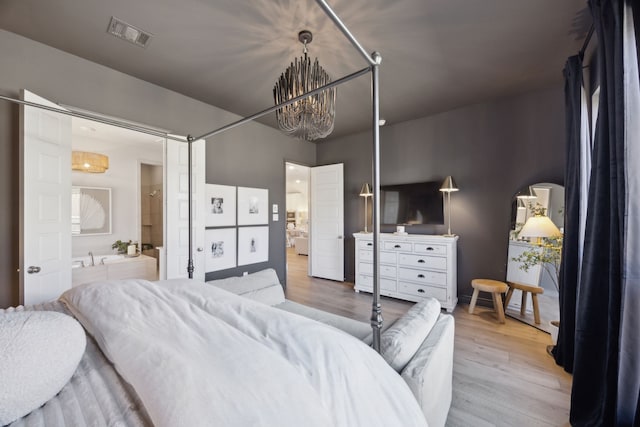 bedroom with connected bathroom, a chandelier, and light wood-type flooring