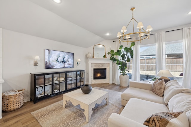 living room with lofted ceiling, wood-type flooring, and a notable chandelier