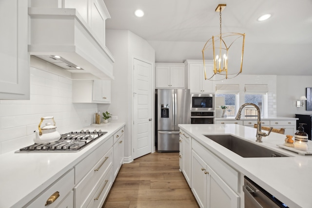 kitchen with white cabinetry, sink, stainless steel appliances, and custom range hood