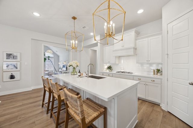 kitchen with pendant lighting, sink, stainless steel gas cooktop, and white cabinets