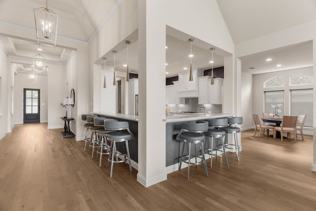 kitchen with white cabinetry, a notable chandelier, pendant lighting, and a breakfast bar area