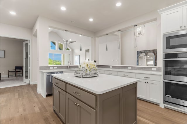 kitchen featuring decorative light fixtures, kitchen peninsula, white cabinets, and appliances with stainless steel finishes