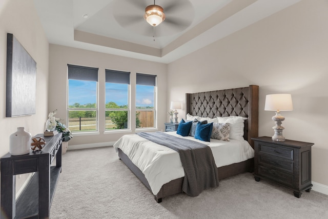 carpeted bedroom with ceiling fan and a raised ceiling