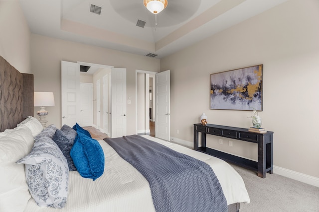 bedroom featuring a raised ceiling, ceiling fan, and carpet