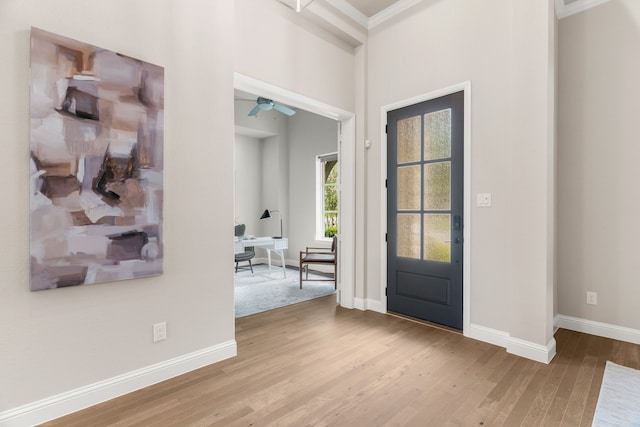 foyer with crown molding, ceiling fan, and light wood-type flooring