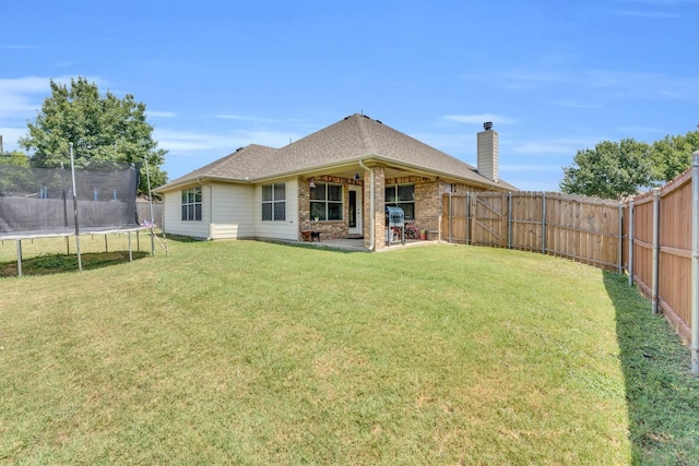 back of house with a patio, a yard, and a trampoline