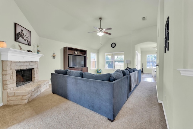 carpeted living room with a fireplace, ceiling fan, and vaulted ceiling