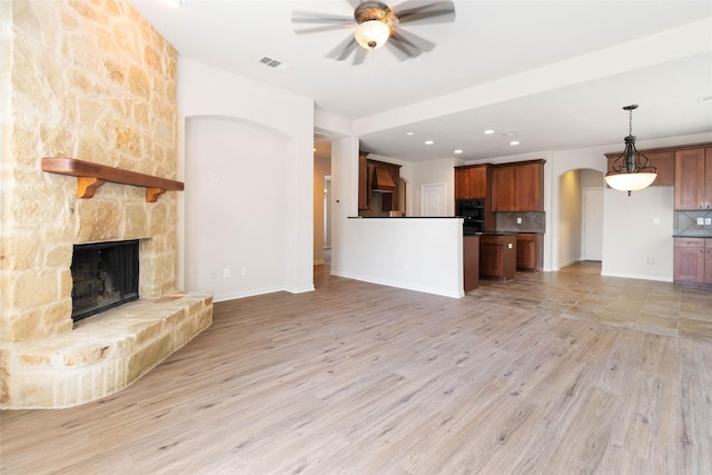 unfurnished living room featuring a fireplace, light hardwood / wood-style floors, and ceiling fan